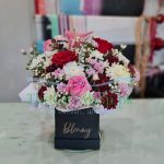 A close-up of a flower box with roses, chrysanthemums and baby’s breath