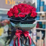 A photo of a round bouquet of 30 imported red roses wrapped in black paper