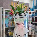 A photo of five white lilies on a blurred gift shop background.