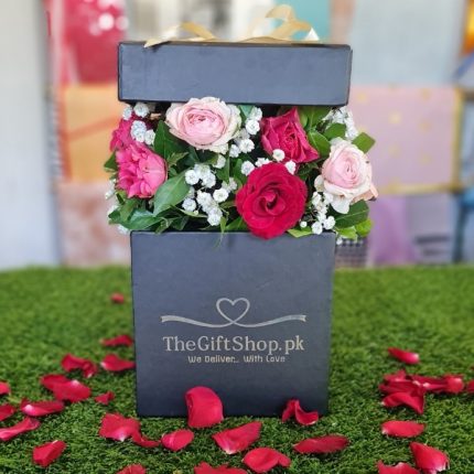 Flair Box - Pink and red roses in a black box with rose petals scattered around.