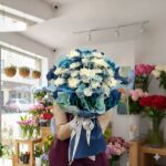 A luxury Aqua Bloom bouquet featuring white chrysanthemums and azure blue flowers in wave-style navy and seafoam wrapping for flower delivery in Pakistan via TheGiftShop.pk.